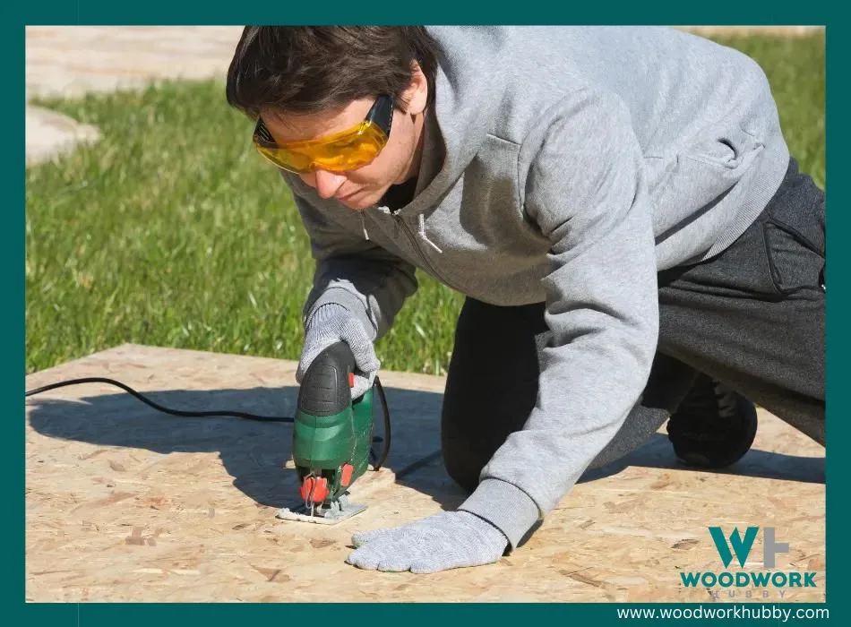 A man wearing goggles and using an electric saw to cut the OSB board